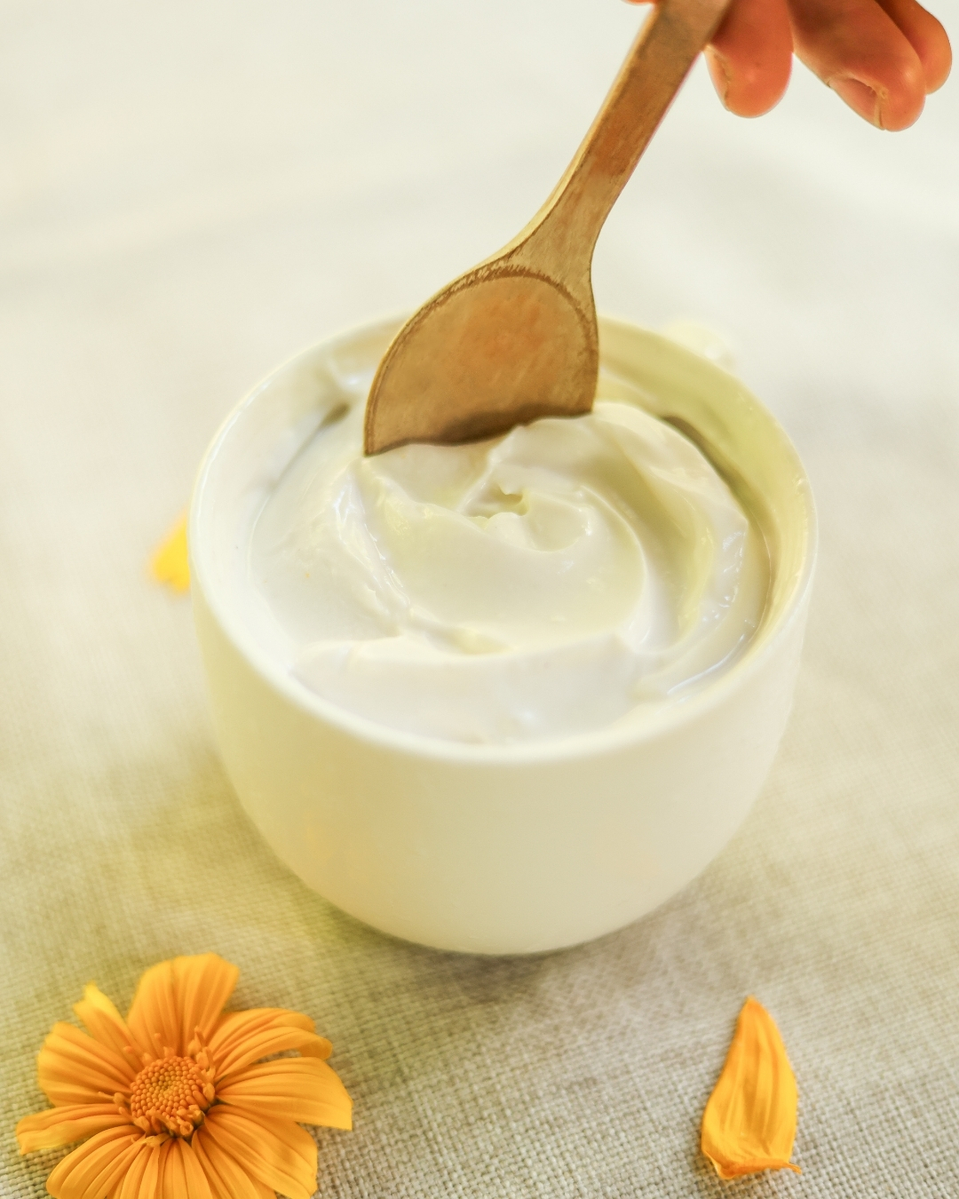 Creamy dairy-free coconut yogurt in a white bowl with a wooden spoon.