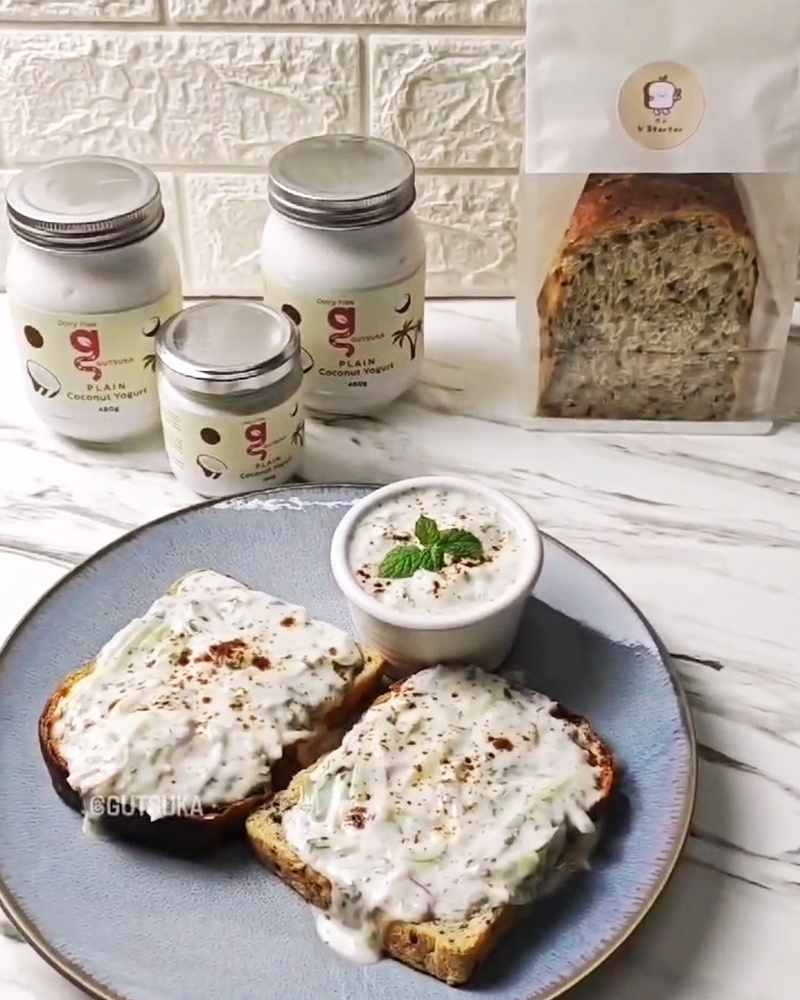 Creamy Tropical Raita spread on toasted bread, with jars of Gutsuka Plain Coconut Yogurt in the background.