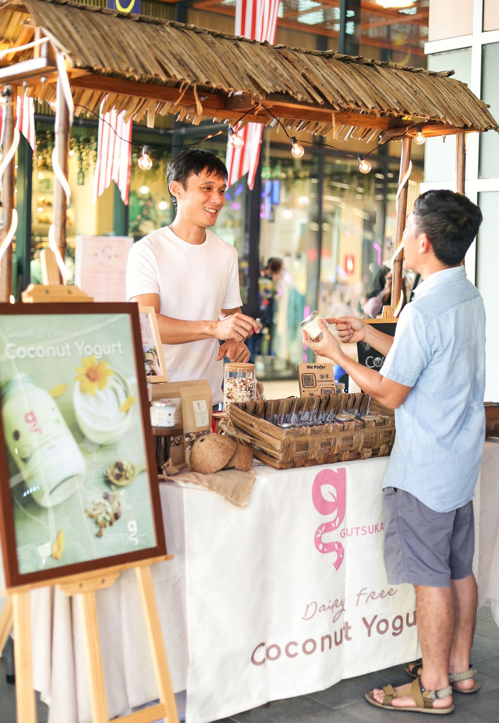 Gutsuka founder Wong explaining dairy-free yogurt to a customer at a Malaysian market stall